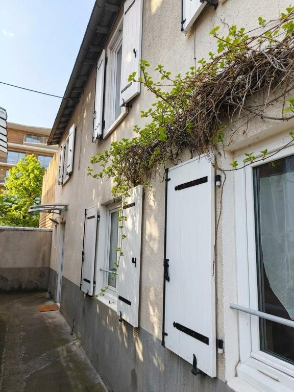 a building with white doors and ivy growing on it at Small townhouse in Clermont-Ferrand