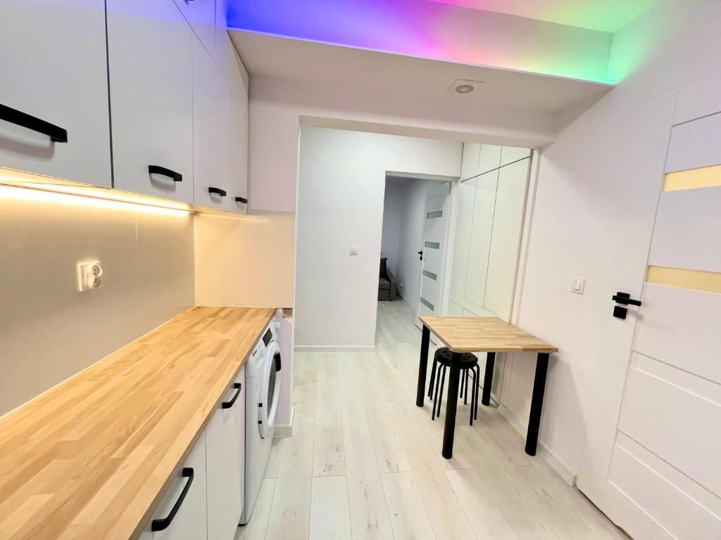 a kitchen with white cabinets and a wooden table at Lubicz Dolny, A1 Apartament 2 pokojowy in Lubicz
