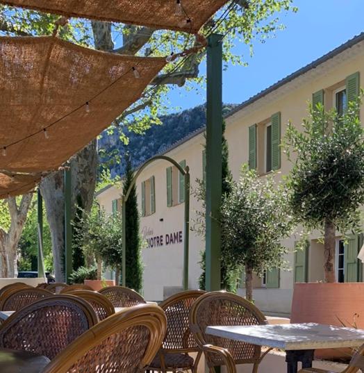 a patio with tables and chairs and a building at Le Relais Notre Dame in Quinson
