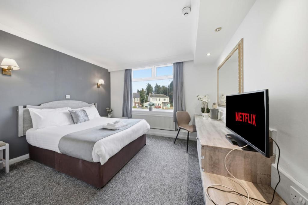 a hotel room with a bed and a tv at The Greyhound Hotel in Leigh