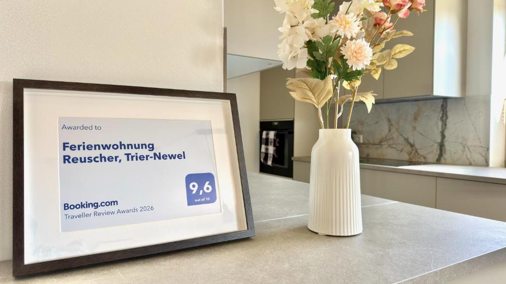 a white vase with flowers sitting next to a framed picture at Ferienwohnung Reuscher, Trier-Newel in Newel