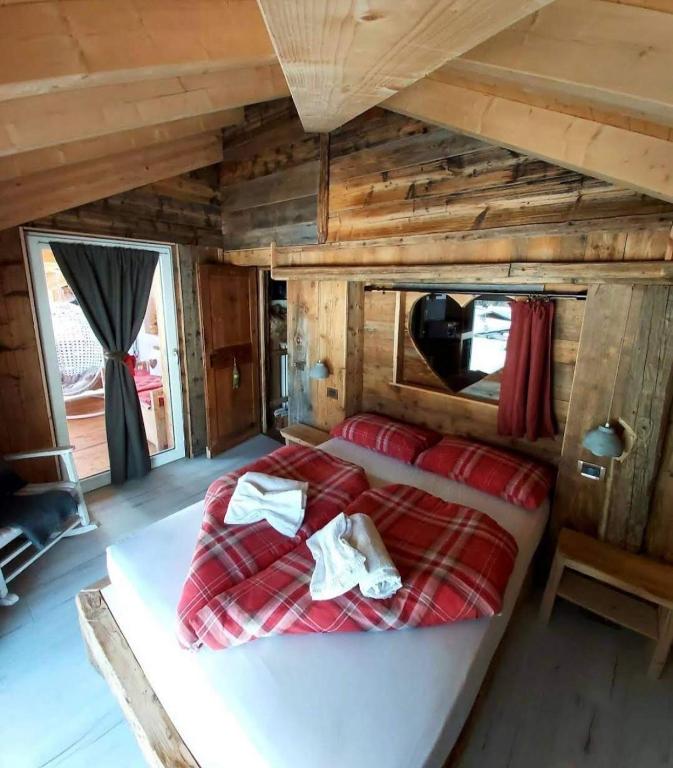 a bed in the middle of a room with wooden walls at Cuore Tana dell'Orso in Campitello di Fassa