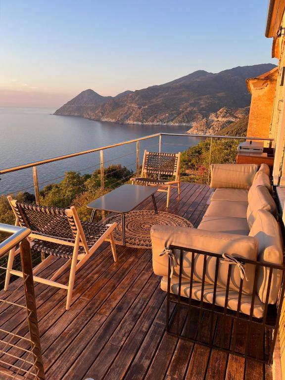 a deck with chairs and a table and a view of the water at Large period house with panoramic view in Canari