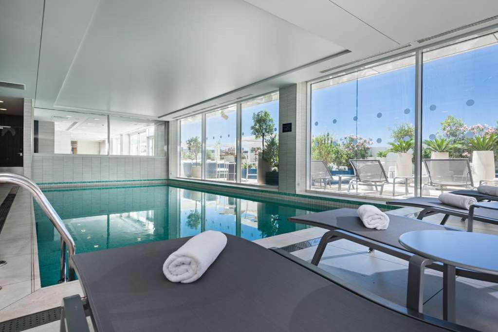 a swimming pool with tables and chairs in a house at Golden Tulip Marseille Euromed in Marseille