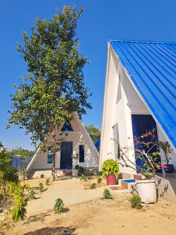 a white building with a blue roof next to a tree at Mung Kham Stays in Jorhat