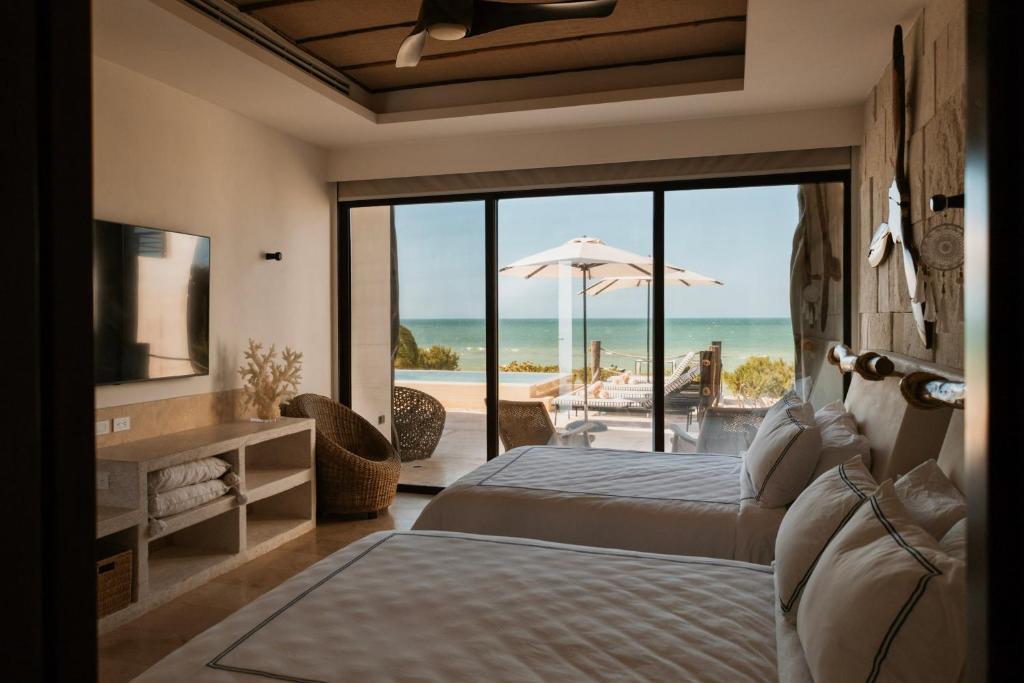 a bedroom with two beds and a view of the beach at Beach House Costa Yucatan by Trobbu Collection in Xtampú