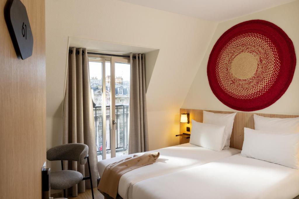 una stanza d'albergo con due letti e un gatto seduto sul letto di Korner République a Parigi