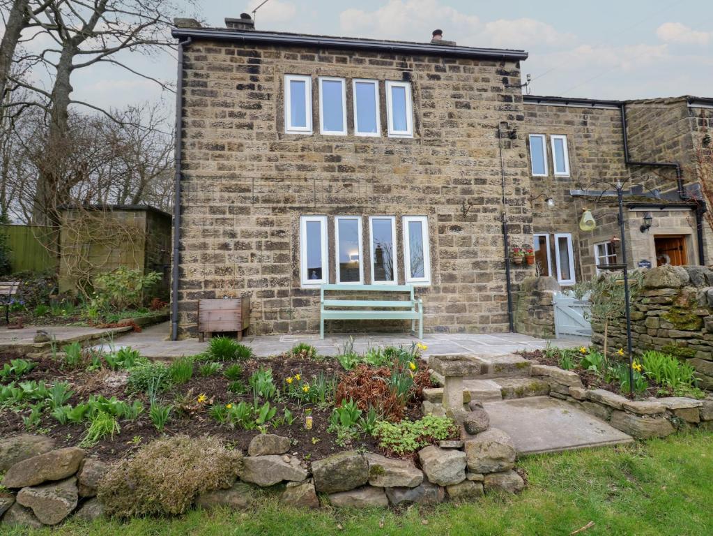 a brick house with a garden in front of it at Barley Cote Farm in Keighley