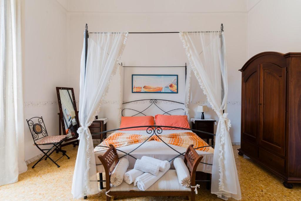 a bedroom with a canopy bed with orange pillows at Piazzetta San Giovanni Specchia in Specchia