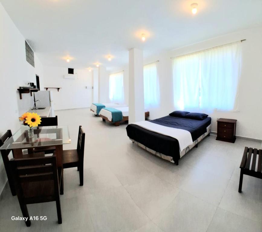 a bedroom with two beds and a table and a desk at Barrio Central in Puerto Ayora