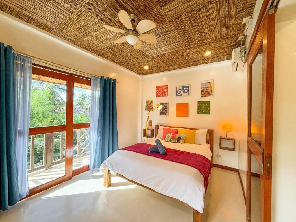 a bedroom with a bed with a ceiling fan at Copacabana Siargao Boutique Hotel & Artcafé in General Luna