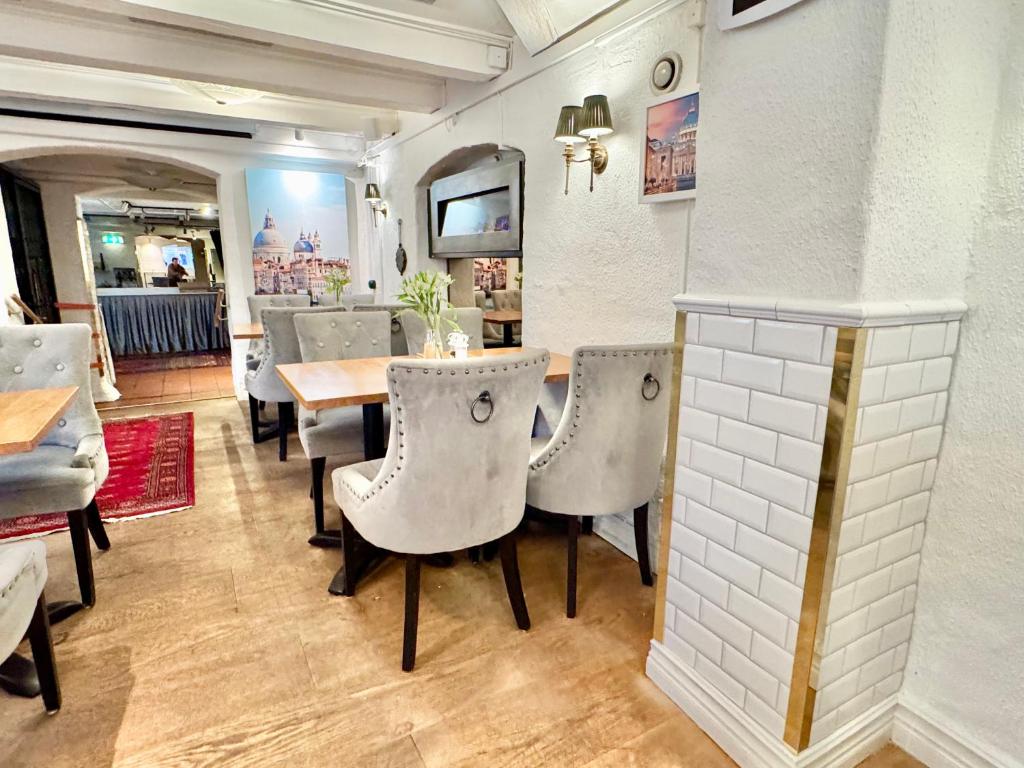 Jasna restauracja z aksamitnymi szarymi krzesłami, drewnianymi stolikami i przytulną atmosferą.
