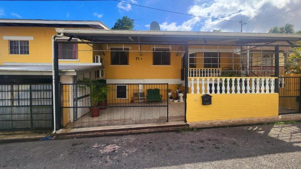 a yellow house with a gate in front of it at Elaine's Hideaway in Point Fortin