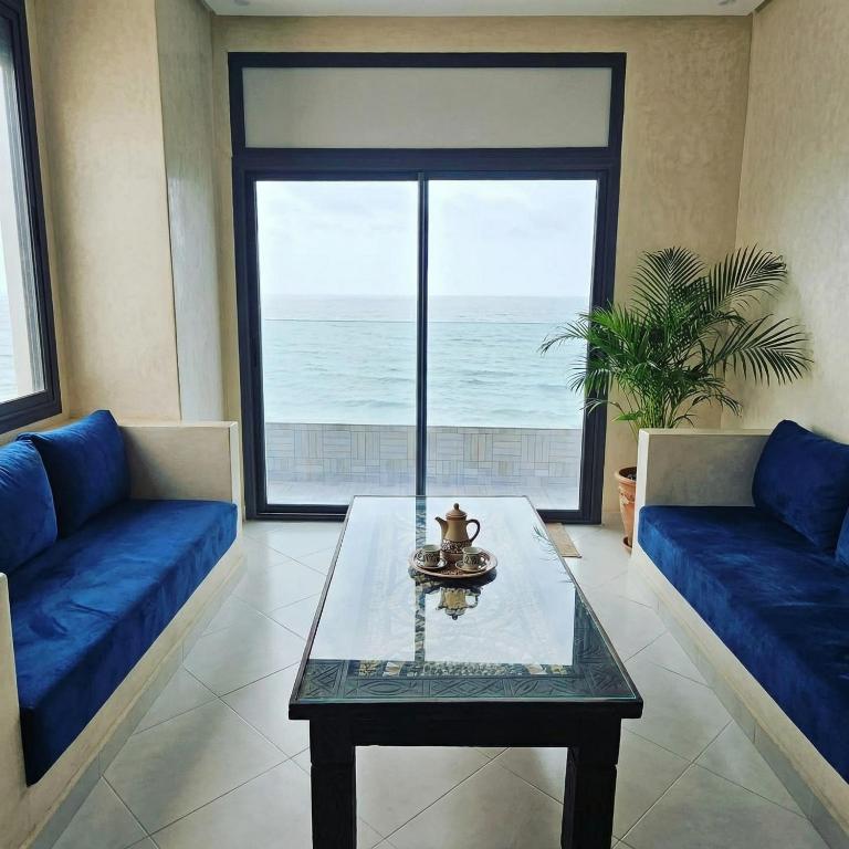 a living room with a table and a view of the ocean at Amouage résidence 3 in Sidi Ifni
