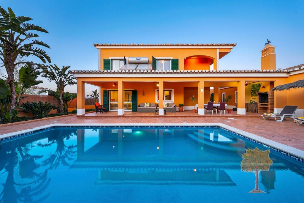 a villa with a swimming pool in front of a house at "Orange Tree Villa in Alvor - South - facing Family Villa with Private Poll" in Alvor