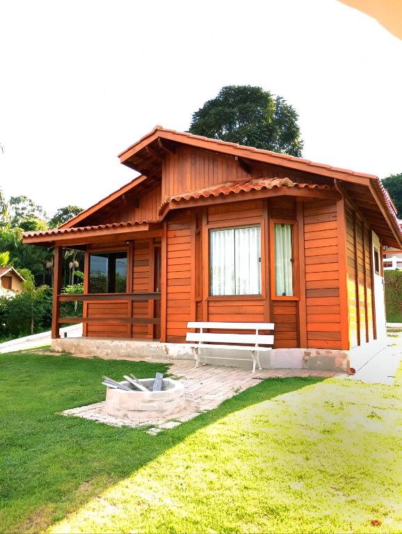 a small wooden cabin with a bench in a yard at Chalés da Preguiça in Pedra Menina