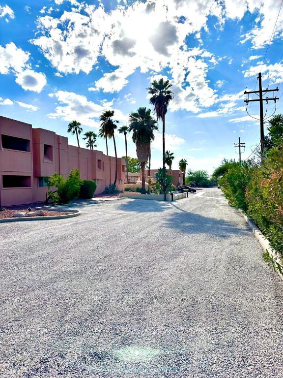 an empty street with palm trees and a building at Flamingo Suites in Tucson
