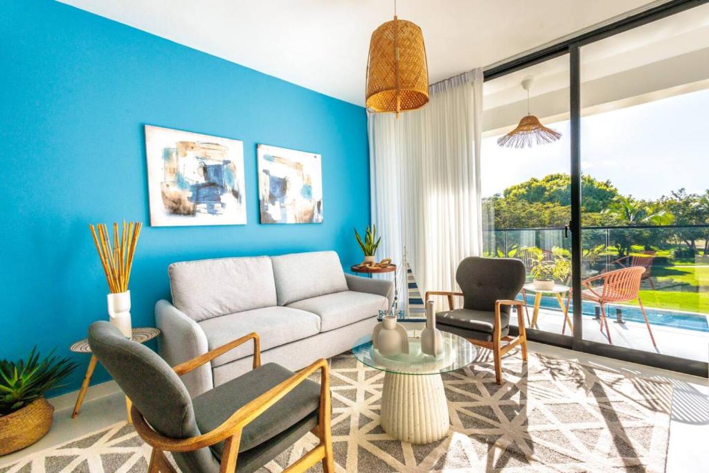 a living room with blue walls and a couch and chairs at Elegant 3BD Condo in Cocotal in Punta Cana