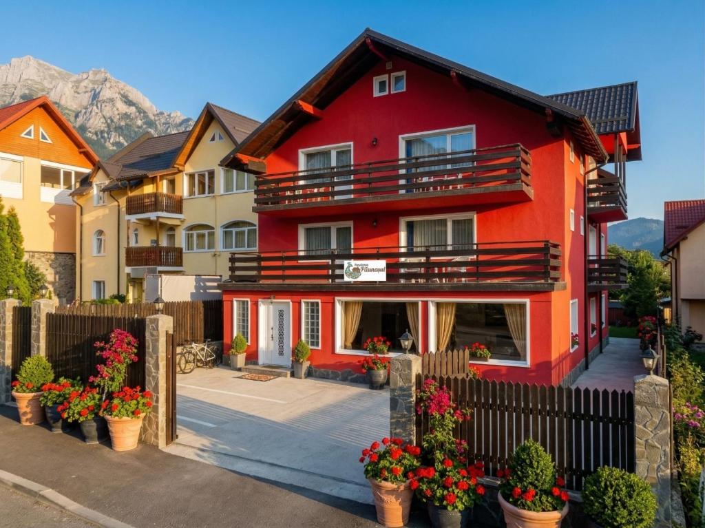 a red house with a fence and some flowers at Pension Paunasul in Buşteni