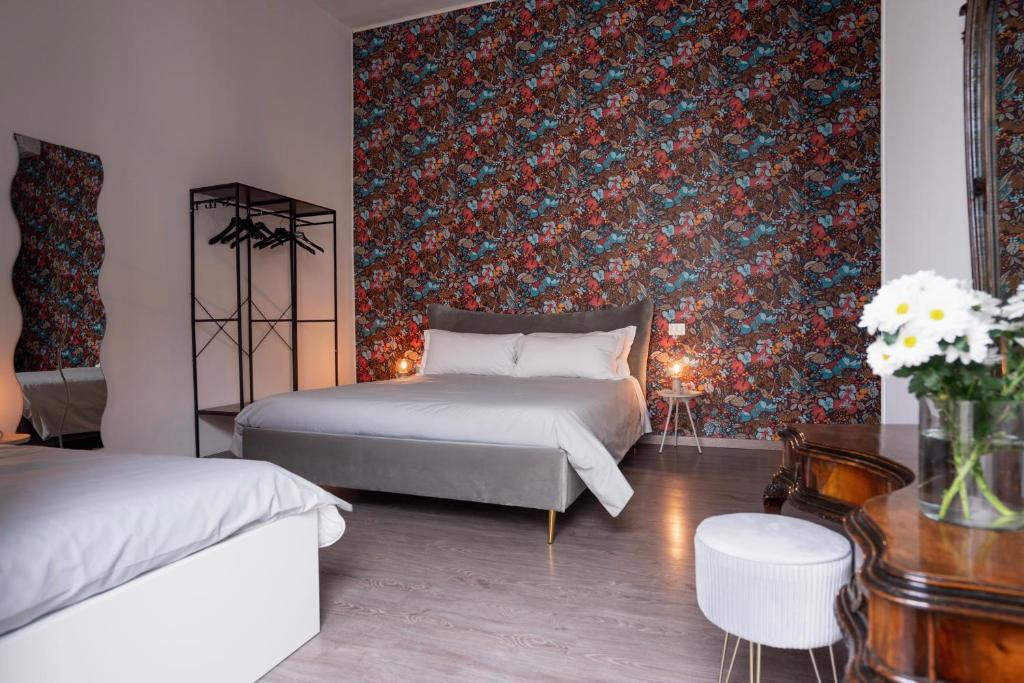 a bedroom with two beds and a floral wall at B&B Università in Catania