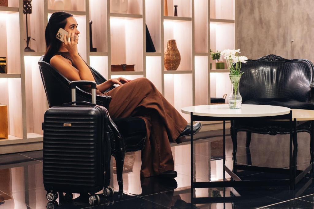 a woman sitting in a chair with a suitcase talking on the phone at 1253 Recoleta Small Hotel in Buenos Aires