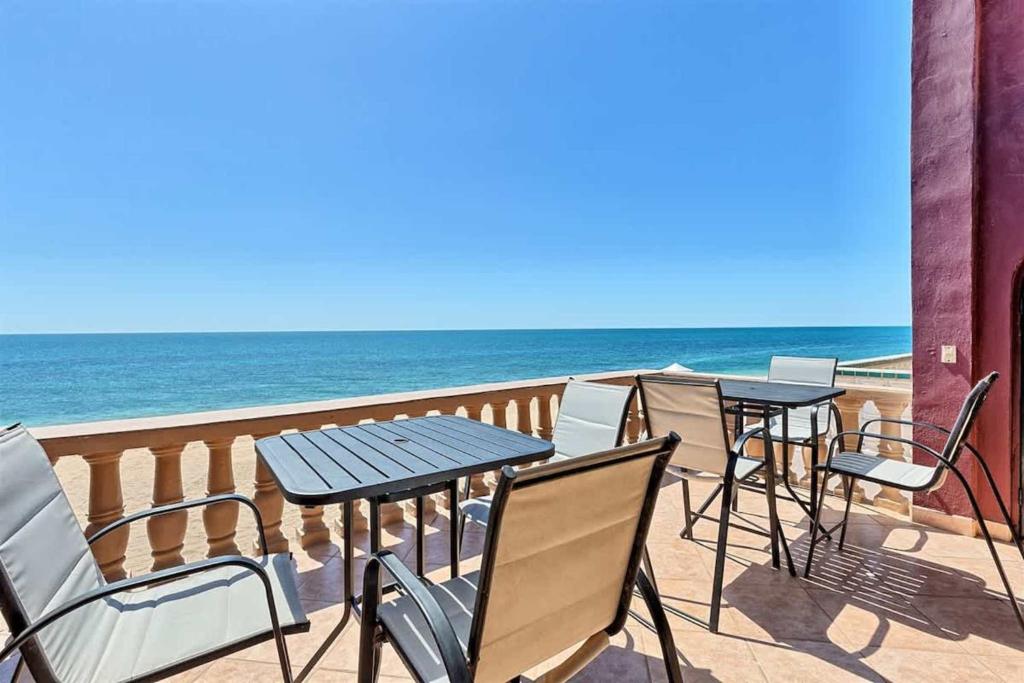two tables and chairs on a balcony with the ocean at Comfortable Beachfront Condo Las Palmas II 11 B in Puerto Peñasco