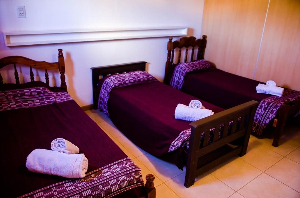 three beds in a room with purple sheets at Departamentos Malargue in Malargüe