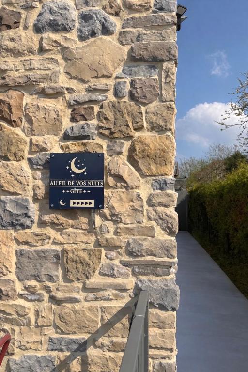 a sign on the side of a stone wall at Au fil de vos nuits in Lustin