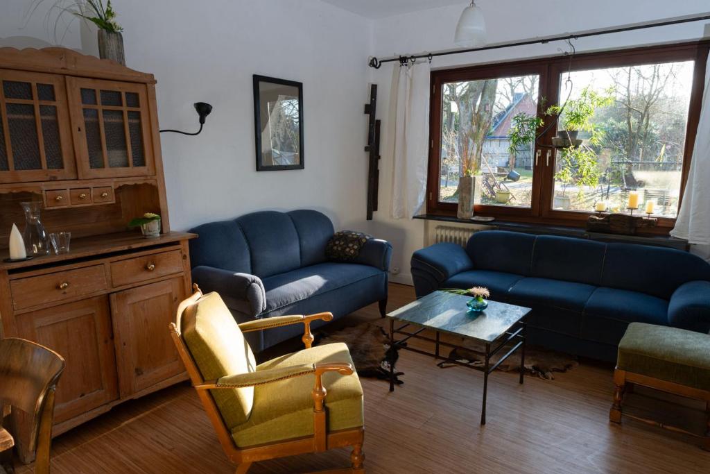a living room with blue couches and a table at Zur Waldschmiede in Kakenstorf