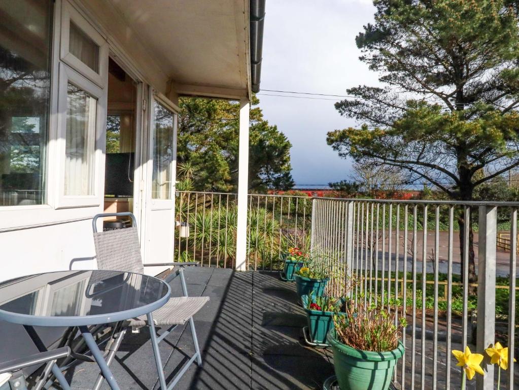 a patio with a table and chairs on a balcony at Sea Glimpse in Dawlish