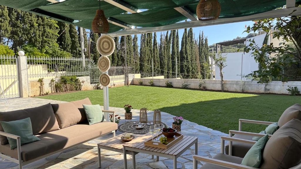 a patio with a couch and a table and a yard at Naiad Villa in Vari