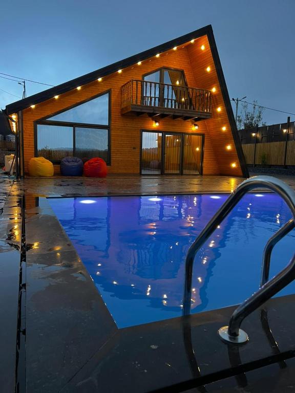 a swimming pool with a house in the background at أكواخ غصُن عجلون in Ajloun