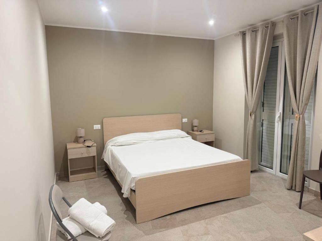 a white bedroom with a bed and a chair at Sofia s Rooms in Falcone