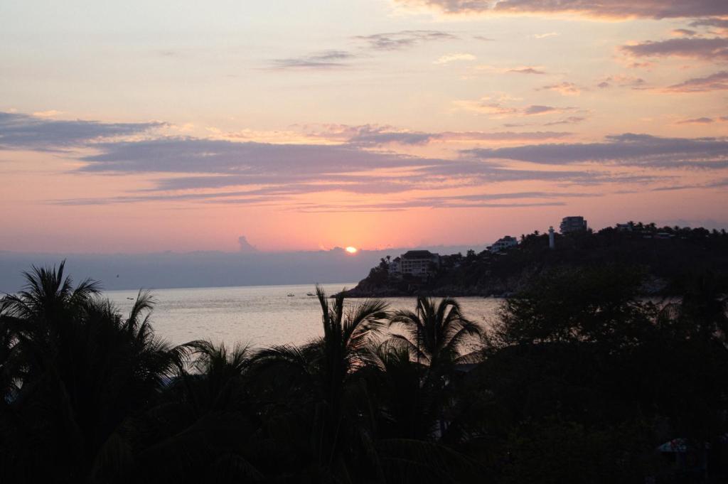 a sunset over the ocean with the sun in the sky at TerraZica hostal in Brisas de Zicatela