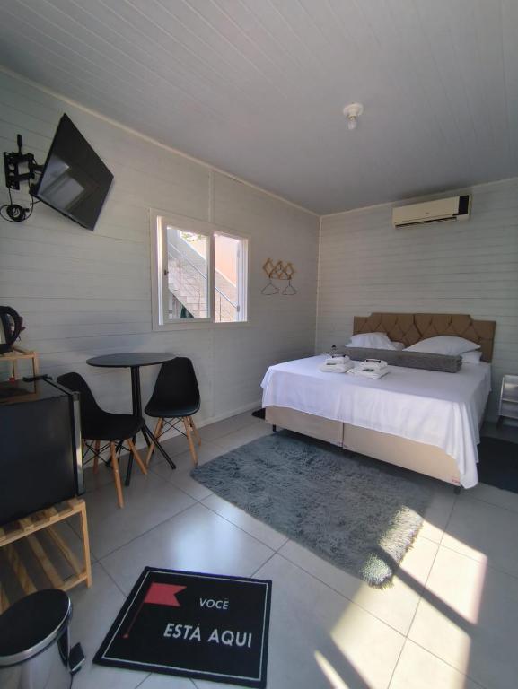 a bedroom with a bed and a table and a television at Aconchego do Lar Hostel in Palhoça