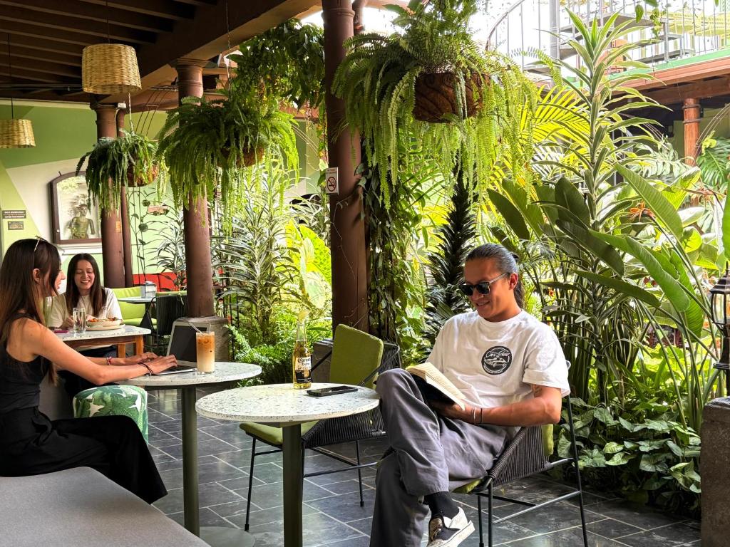 a man sitting at a table with a laptop in a restaurant at Tropicana La Catedral in Antigua Guatemala