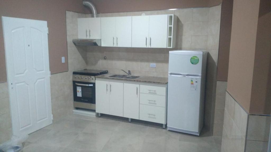 a kitchen with white cabinets and a white refrigerator at Departamentos 12 de Mayo in Salsipuedes