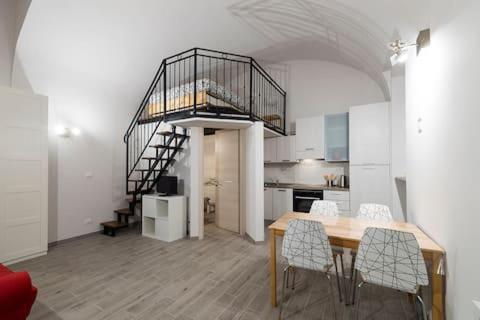 a kitchen with a dining table and a spiral staircase at Monolocale Piazza Garibaldi in Saluzzo