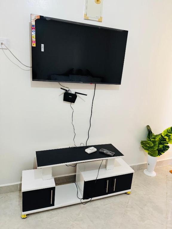 a living room with a tv on a white wall at Bella apartment studios town in Meru