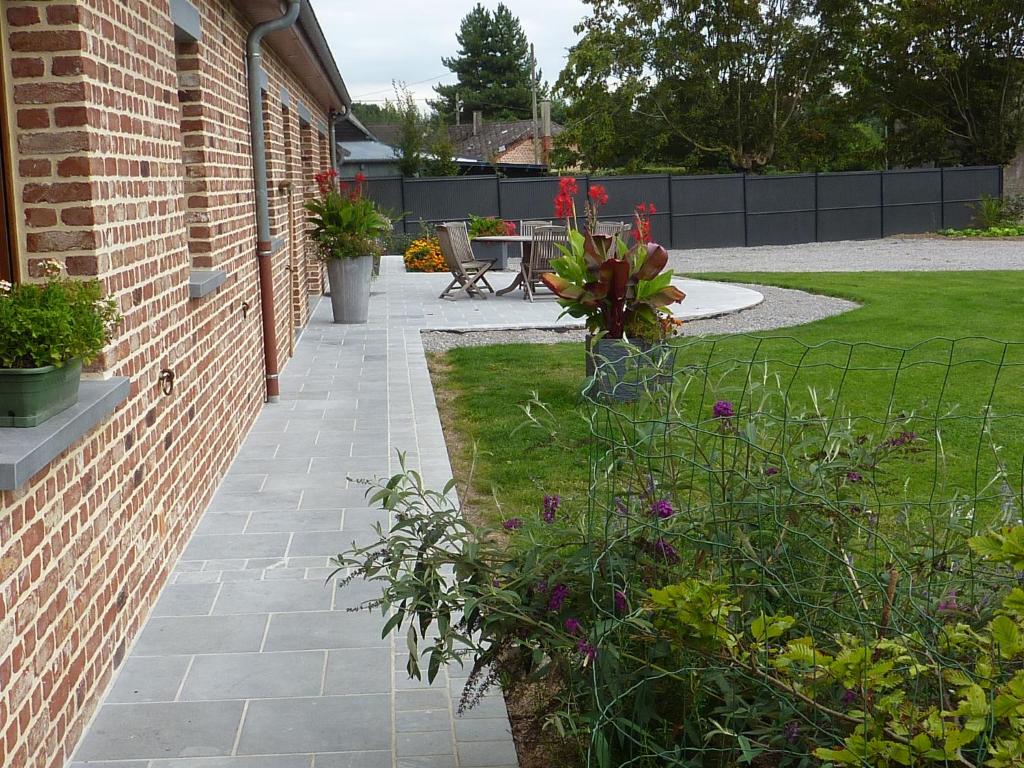 einen Garten mit einer Ziegelwand und einer Terrasse in der Unterkunft Le Courtil in Buironfosse