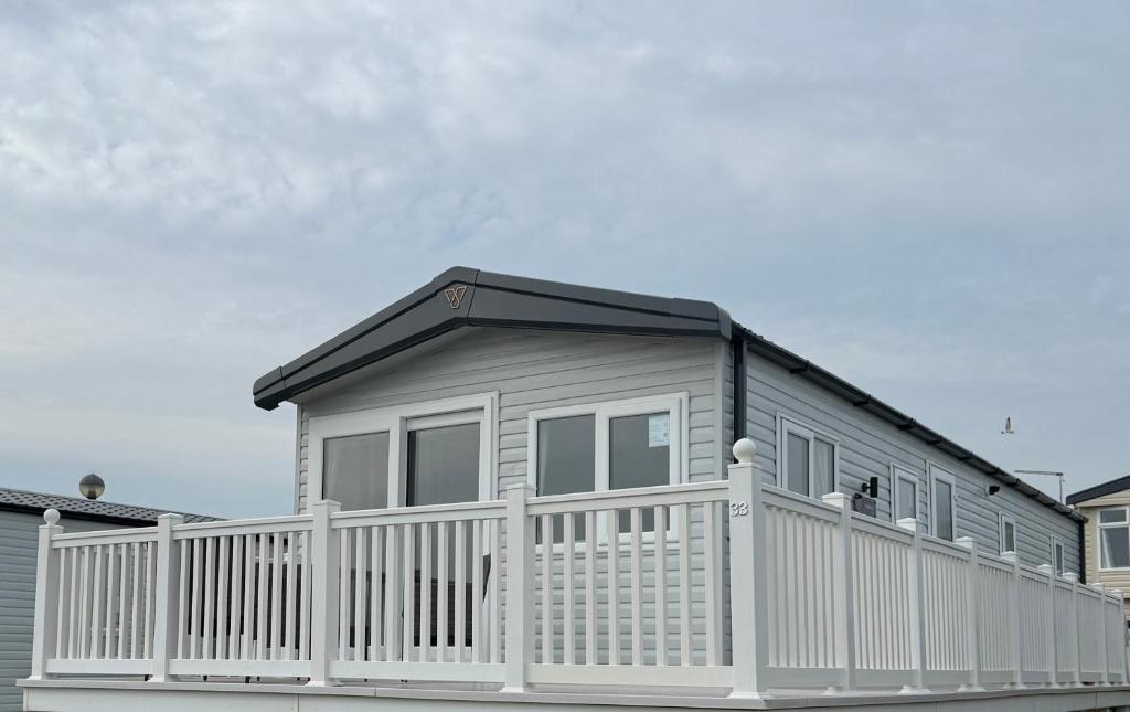 a small house with a white fence at Luxury 3 bed sleeps 8 caravan with sea view in Exmouth