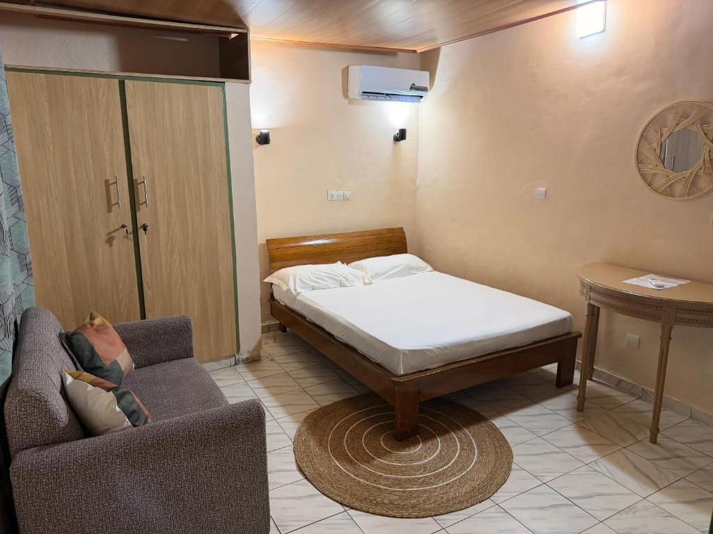 a bedroom with a bed and a couch and a chair at Studio spacieux Aéroport FHB in Abidjan