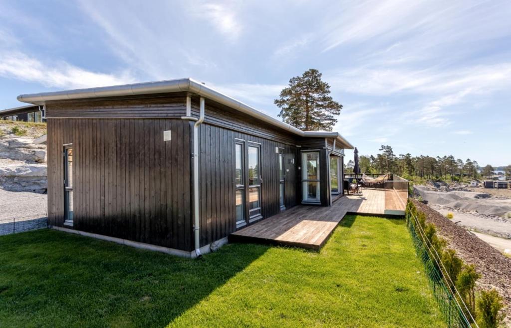 a small house with a deck and grass at Modern cabin with panoramic views in Porsgrunn