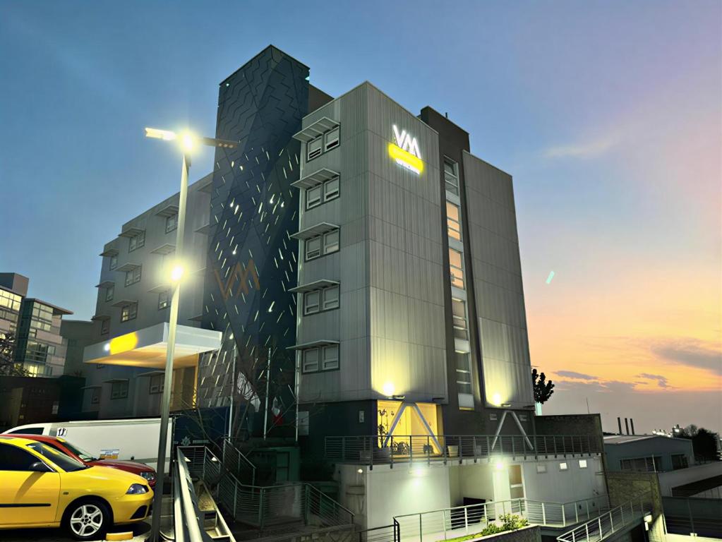 a yellow car parked in front of a building at Hotel VM Express Queretaro in Mendiola