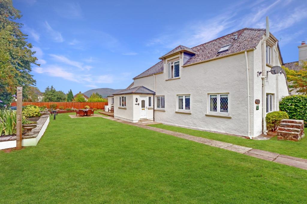 a white house with a green yard at Plum Tree Cottage Porlock in Porlock