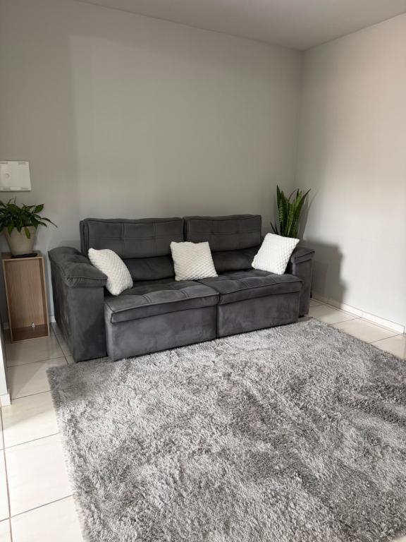 a black leather couch in a living room with a rug at Apartamento Sabrina in Curitiba