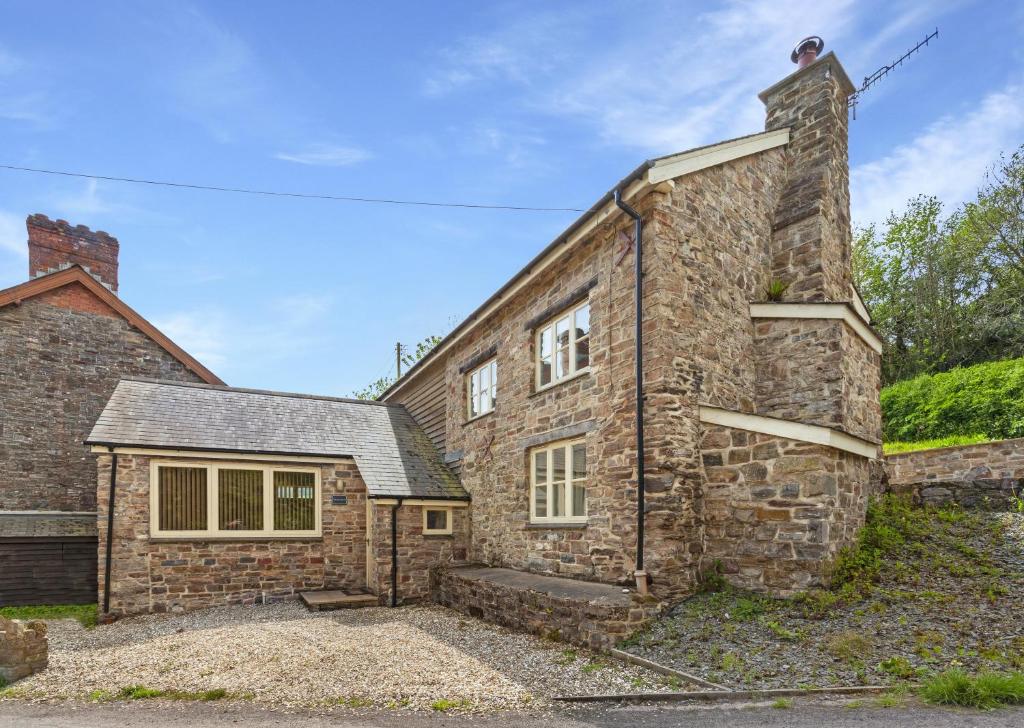 an old stone house with a brick building at The Mill House Bampton in Bampton