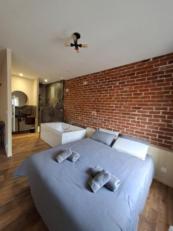 a large bed in a room with a brick wall at Spa d'Assier in Feurs