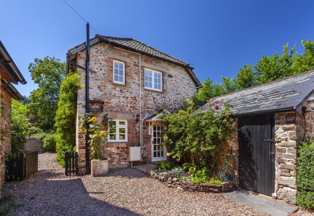 an old stone house with a garage at Luccombe Cottage Luccombe in Luccombe