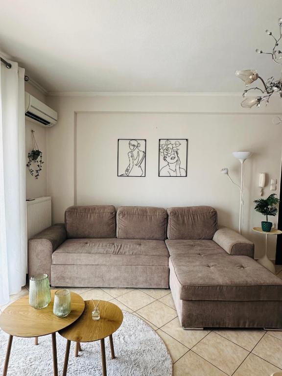 a living room with a brown couch and a table at Artemis apartment in Nea Peramos